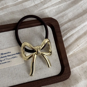 Detailed shot of a vintage gold bow metal hair tie on a decorative fabric tray