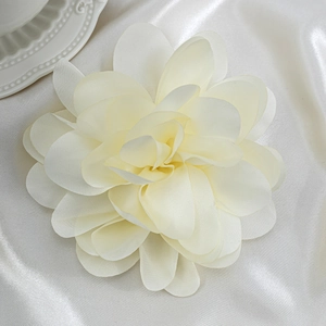 Detailed top view of cream silk rose flower brooch on elegant white satin backdrop
