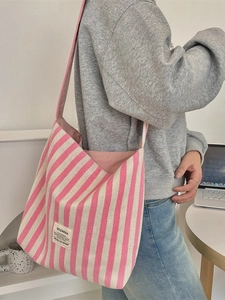 Borsa tote in tela a righe rosa e beige mostrata indossata a spalla in un contesto quotidiano