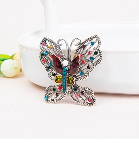 Detail of colorful crystal butterfly brooch with intricate hollow alloy filigree design