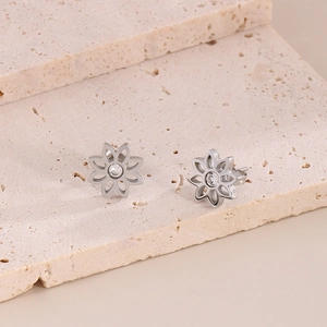Close-up of silver daisy flower stud earrings with center clear crystal on stone