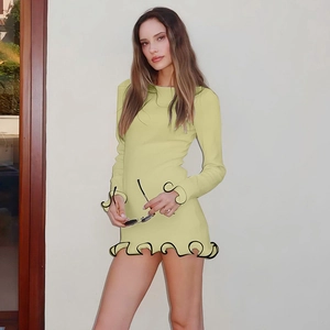 Detalle de vestido de punto amarillo claro con volantes negros en puños y dobladillo