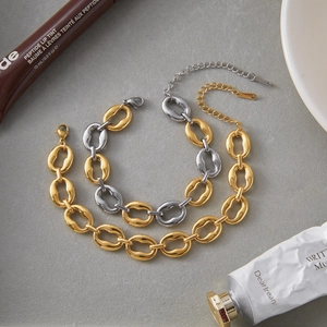 Close-up of gold and silver two-tone chunky link chains with lobster clasps and polished finish