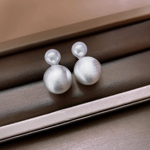 Macro detail of French retro double ball earrings with brushed silver finish and white pearl