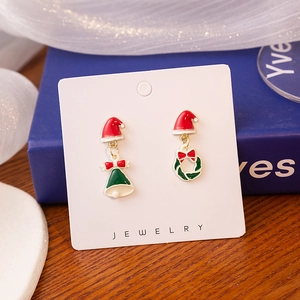 Detail shot of asymmetric Christmas earrings with Santa hat and wreath charms