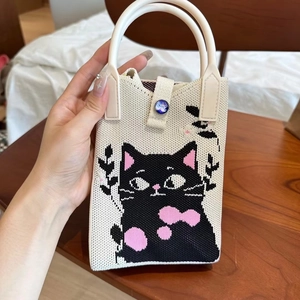 Détail d'un mini sac à bandoulière en tricot avec motif chat et poignées blanches lisses
