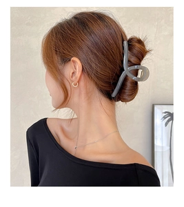 Macro detail of dark grey hair claw clip securing a thick bun hairstyle on model