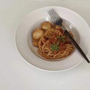Top view of minimalist white ceramic pasta bowl with textured rim and meatballs
