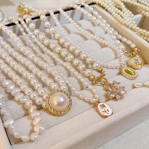 Gros plan de colliers de perles vintage avec pendentifs dorés sur un plateau en velours