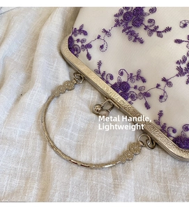 Close-up of vintage white mesh lace bag with purple floral embroidery and metal handle