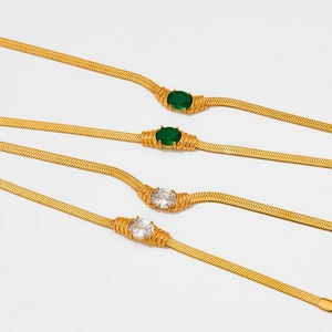 Detail of gold snake chains featuring green and clear oval gemstone pendants in rows