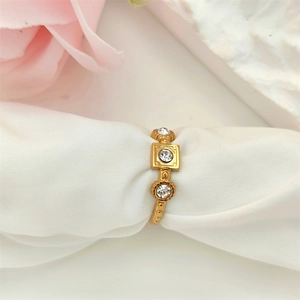 Macro shot of gold vintage textured ring with three clear crystals on white silk