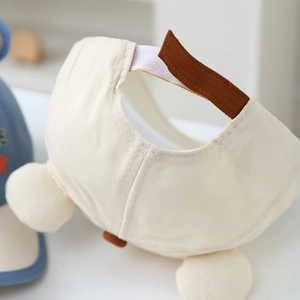 Detailansicht der Rückseite einer cremefarbenen Kinder-Baseballkappe mit braunem Riemen