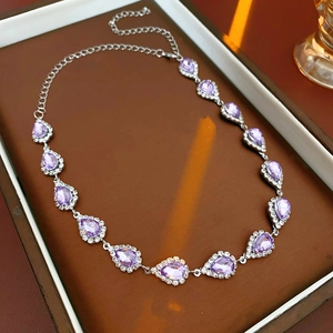 Detailed macro view of vintage silver necklace with purple teardrop crystals in a jewelry box