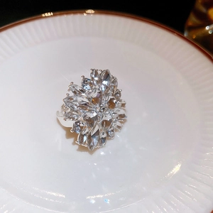 Macro shot of silver flower ring with sparkling crystals on textured white plate