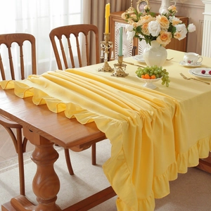 Elegant yellow tablecloth with ruffled edges on a dining table in a cozy home setting