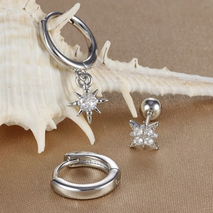 Macro shot of silver star stud earrings and hoop set displayed on a white seashell