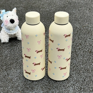 Vue détaillée de deux bouteilles en inox crème avec motifs de teckel et rubans