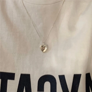 Detailed view of an irregular silver 925 heart pendant necklace on a white t-shirt