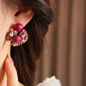 Macro shot of berry purple resin flower earring with sparkling rhinestones on model