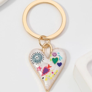 Porte-clés cœur doré avec texture marbre blanc, charms œil et étoiles sur fond beige clair