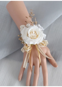 Dettaglio del corsage da polso con rosa bianca artificiale, perle e foglie dorate