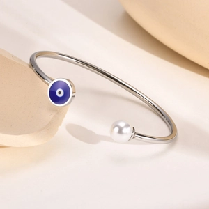 Detail of silver stainless steel cuff bracelet with evil eye charm and white pearl