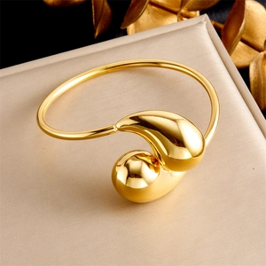 Gros plan détaillé d'un bracelet jonc goutte d'or sur une surface texturée neutre