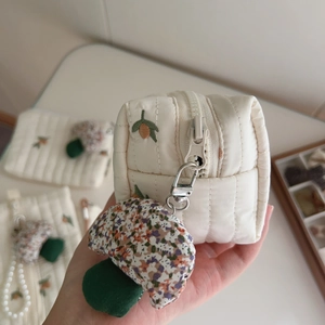 Detail of beige quilted bag with acorn embroidery and fabric mushroom charm