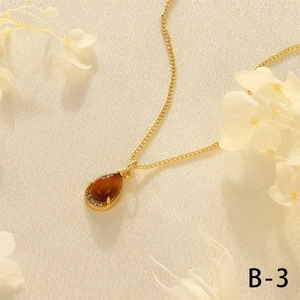 Detail of 18K gold-plated cuban chain with brown teardrop gemstone and micro-pave crystals