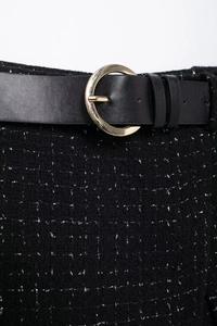 Détail de tweed noir avec fils métalliques et ceinture en cuir à boucle dorée en croissant