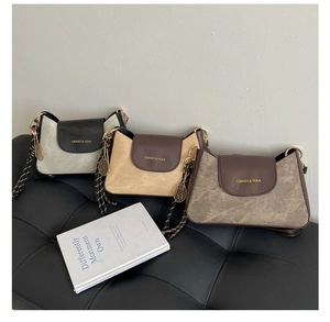 Detailed view of three minimalist patchwork crossbody bags on a black leather sofa