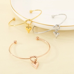 Detailed view of knot bracelets with heart charms in gold, silver, and rose gold finishes