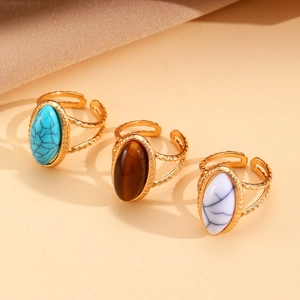 Tres anillos vintage dorados con ojo de tigre, turquesa y howlita sobre tela de seda