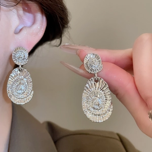 Close-up of silver earrings with textured spiral design worn by a model in soft light