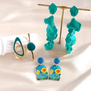 Detailed view of acrylic petal earrings and floral pendant on elegant silk fabric
