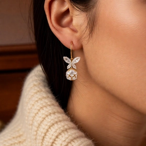 Détail de boucles d'oreilles papillon dorées avec zircones étincelantes sur un modèle