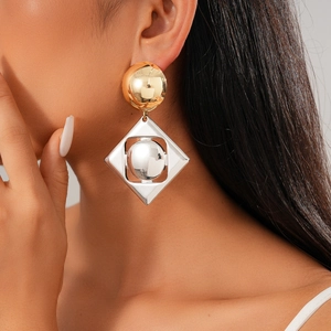Close-up of geometric gold and silver metal earrings worn by a model for a stylish look