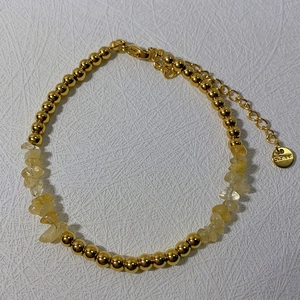 Detail of 18k gold plated stainless steel bead bracelet with yellow natural stone and tag