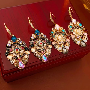 Baroque vintage gold-tone drop earrings with colorful crystals on a wooden jewelry box
