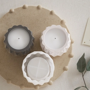 Drie geometrische kaarsenhouders in grijs en wit op een beige decoratief dienblad van hars