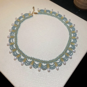 Macro detail of sky blue beaded lace necklace with gold accents and pearl pendants