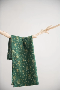 Vue détaillée d'une serviette en lin vert foncé avec motifs de Noël dorés et flocons