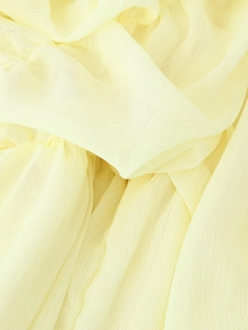 Macro shot of yellow pleated chiffon fabric detail showing lightweight texture and grain