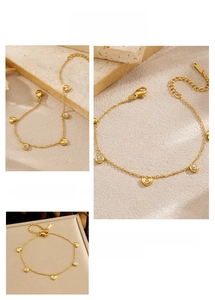 Detail of a gold stainless steel chain bracelet with heart and round zircon pendants