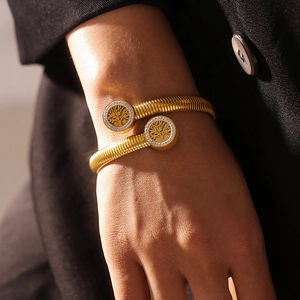 Gold plated tree of life bangle with crystals on a model wearing a black blazer