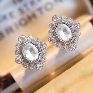 Macro shot of oval white zircon earrings with a halo flower setting in a jewelry box