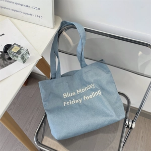 Dettaglio del testo ricamato Blue Monday su una borsa tote in denim azzurro chiaro