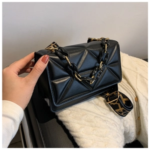 Close-up of black geometric quilted crossbody bag with gold chain and printed wide strap