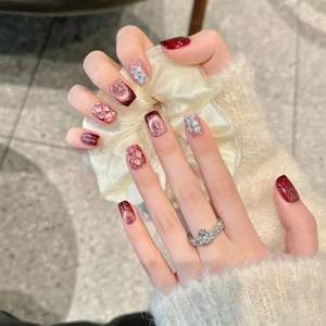 Handmade wine red cat eye press-on nails with glitter and plaid patterns on model hand